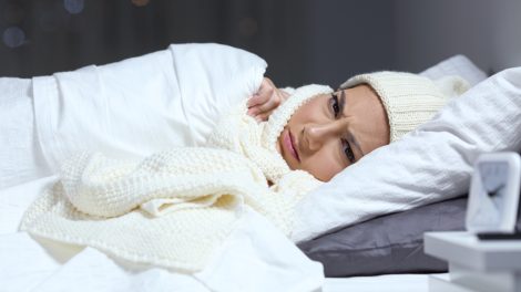 nő fázik az ágyban ezért sapkában sálban alaszik