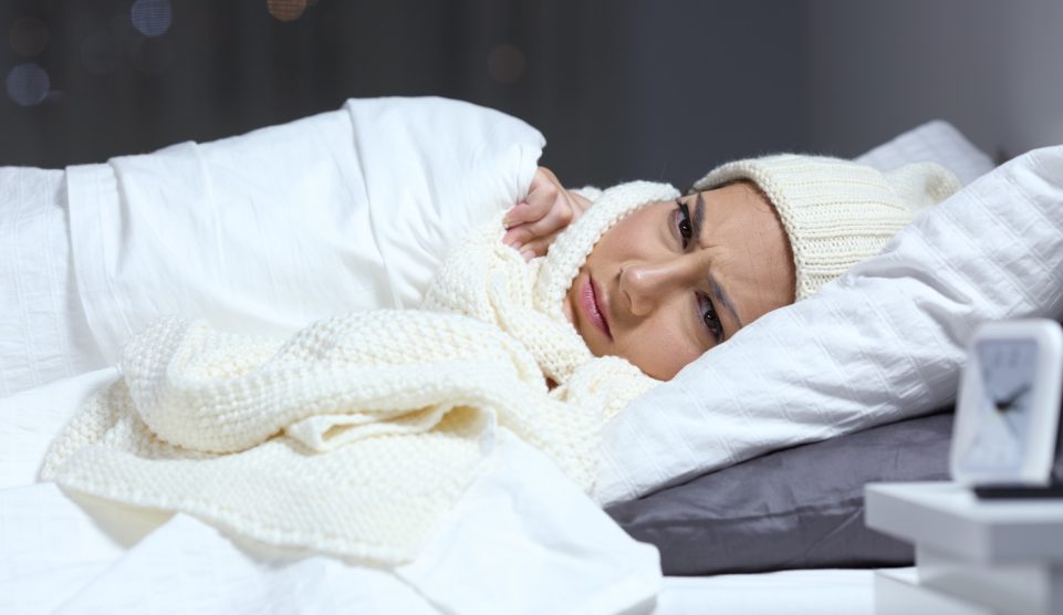 nő fázik az ágyban ezért sapkában sálban alaszik