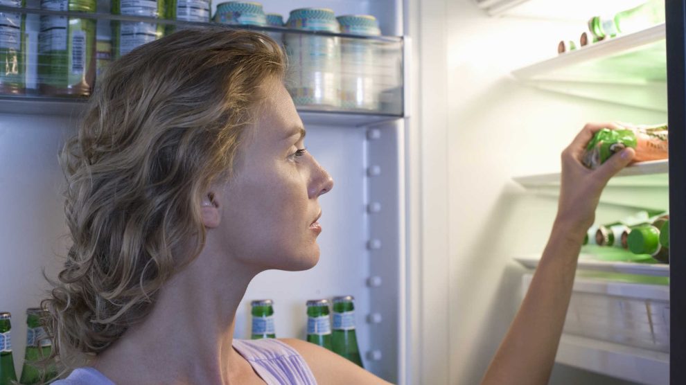 nő kivesz valamit a hűtőből