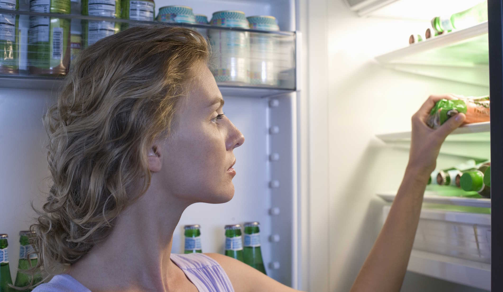 nő kivesz valamit a hűtőből