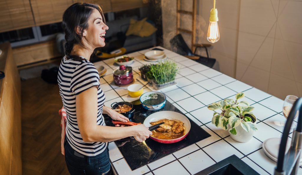 indukciós főzőlapon főz boldogan egy nő