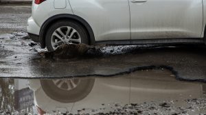 autó hajt bele a kátyúba