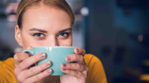 nő maga elé teszi a bögréjét