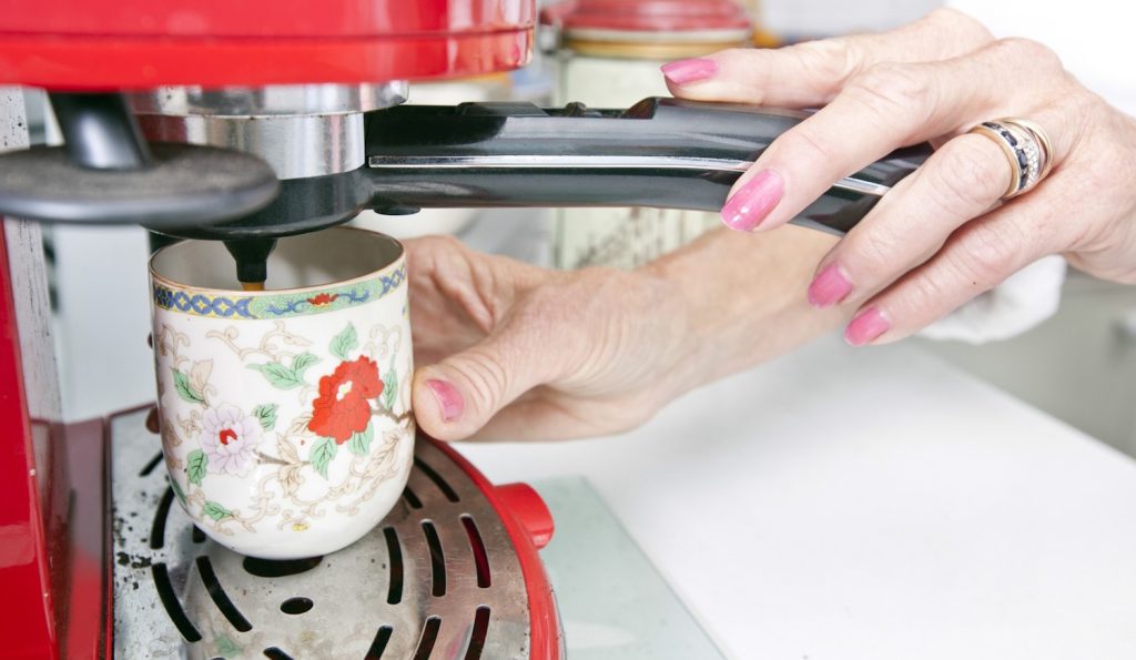 koszos karos kávéfőzőn kávét főz egy nő