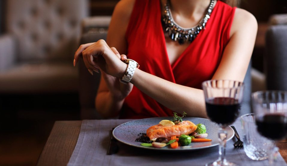 nő étteremben nézi az óráját