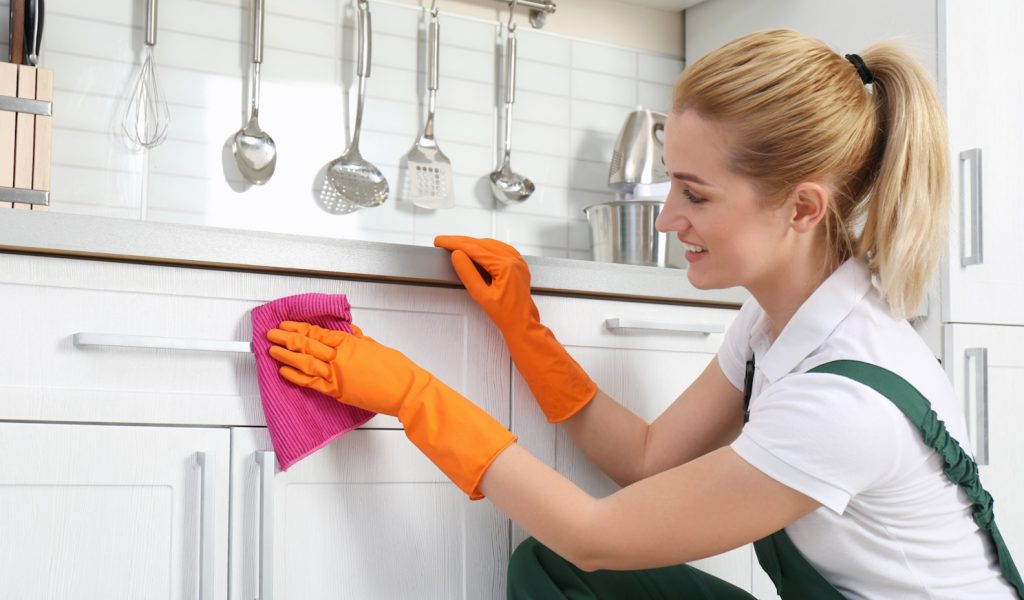 konyhaszekrényt zsírtalanít takarít egy fiatal szőke nő