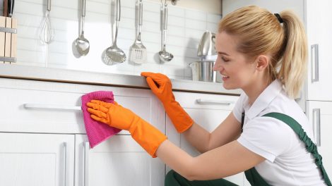 konyhaszekrényt zsírtalanít takarít egy fiatal szőke nő