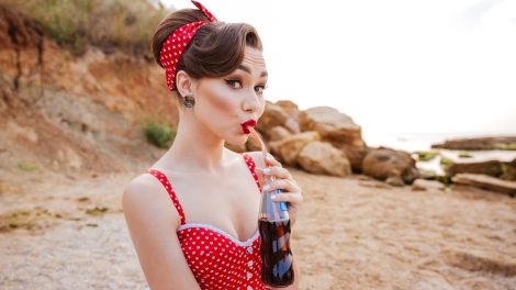 pinup girlnek öltözött lány ligh kólát iszik a tengerparton