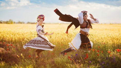 magyar népviseletbe öltözött fiata pár táncol a búzamezőn