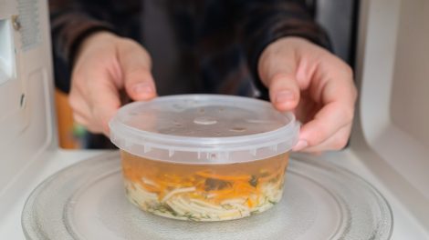 műanyag dobozban húslevest tesz a mikróba egy férfi