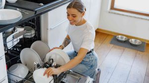 fiatal nő pakol be a mosogatógépbe