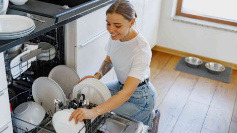 fiatal nő pakol be a mosogatógépbe