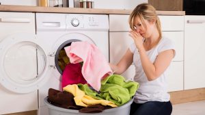 Fiatal nő szedi ki a frissen mosott büdös ruhákat a mosógépből