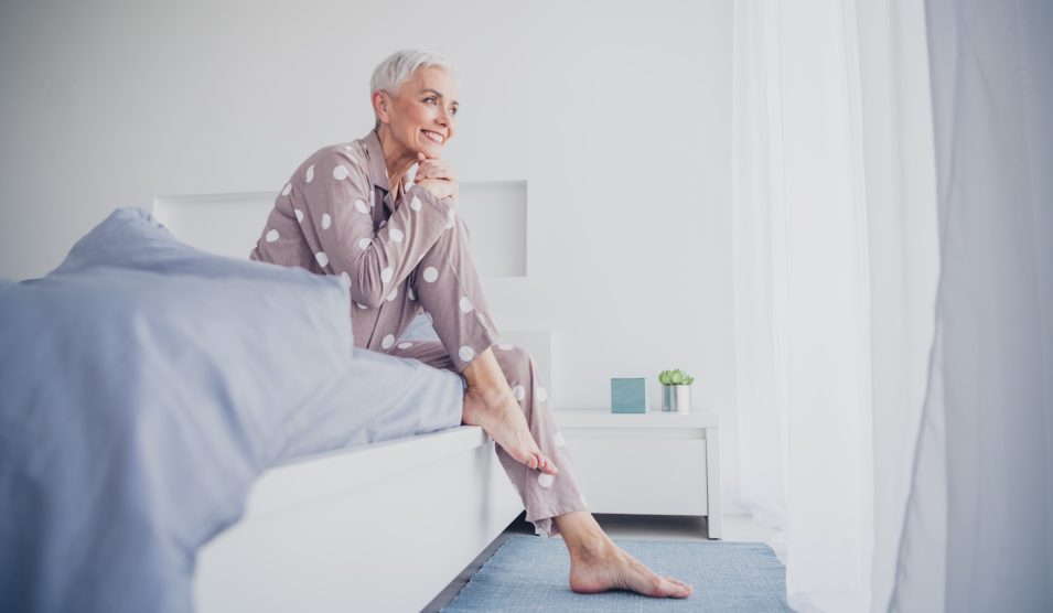 idős nő kel fel reggel vidáman az ágyból