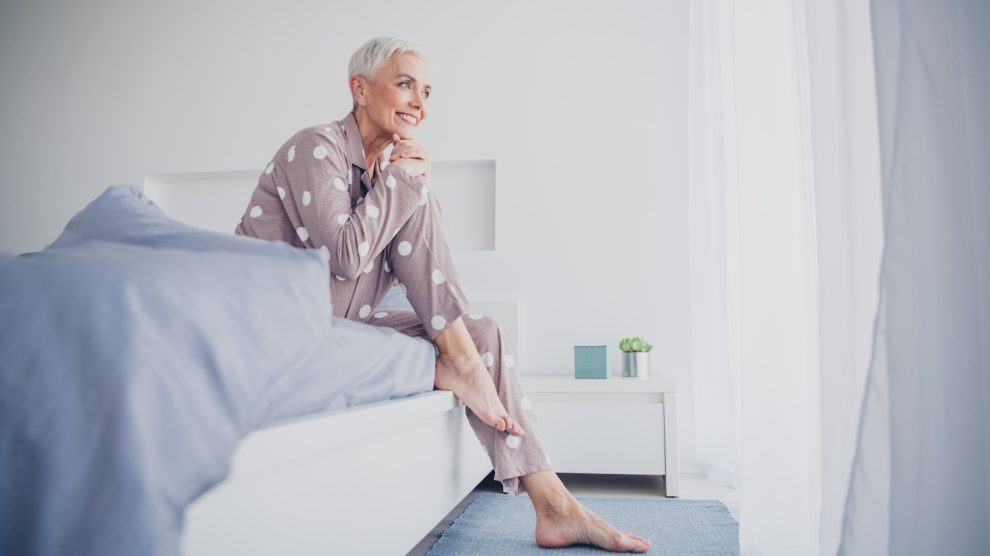 idős nő kel fel reggel vidáman az ágyból