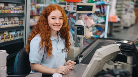 vörös pénztáros lány mosolyog