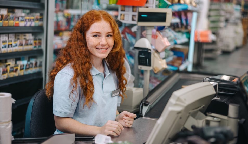 vörös pénztáros lány mosolyog