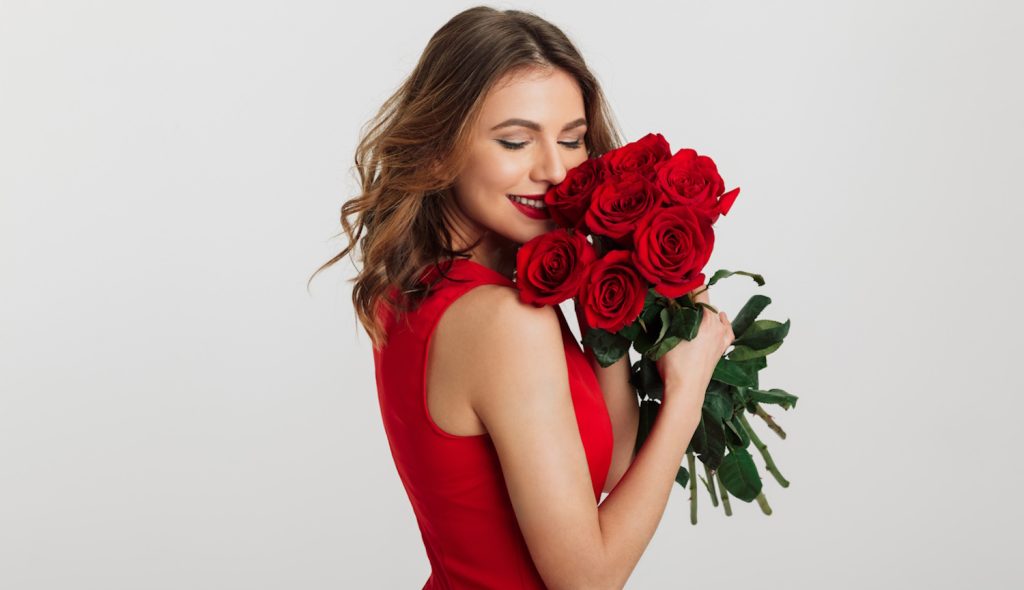 vörös rózsacsokrot szagol egy szép fiatal nő valentin napon