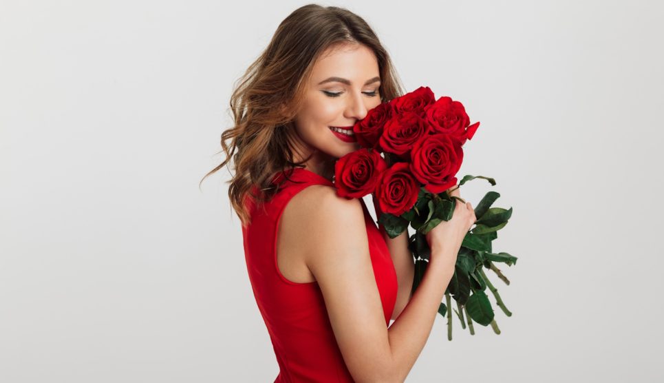 vörös rózsacsokrot szagol egy szép fiatal nő valentin napon