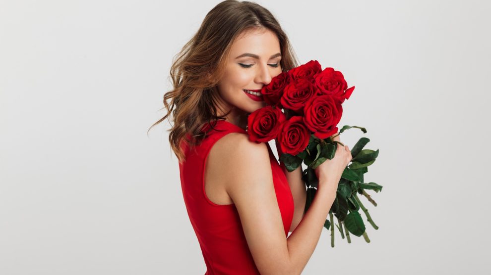 vörös rózsacsokrot szagol egy szép fiatal nő valentin napon