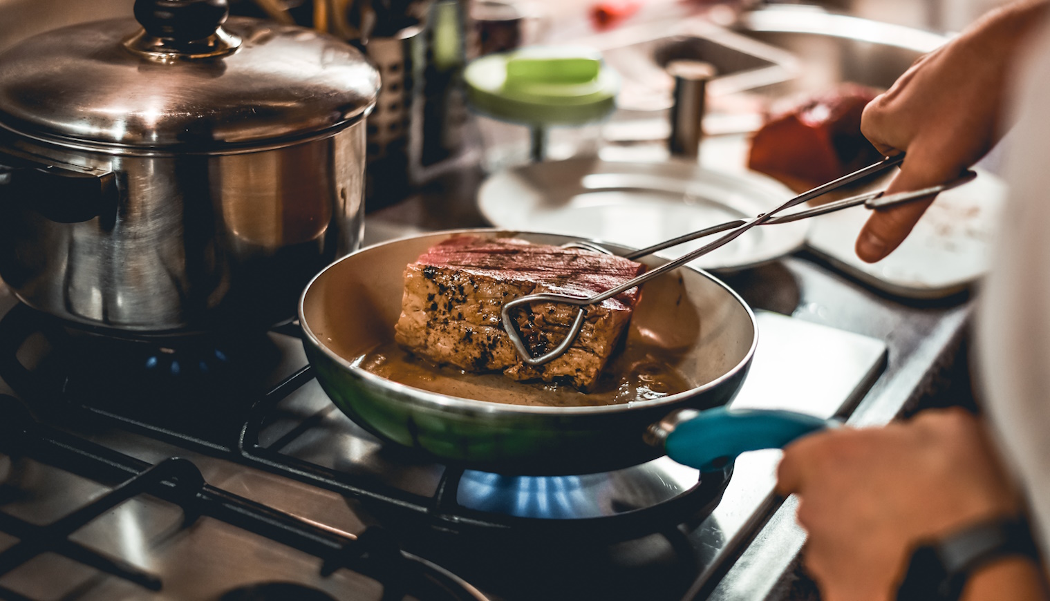 nő nagy darab húst süt serpenyőben minden oldaláén kérgesíti