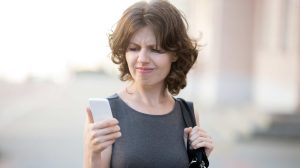 nő séta közben nézi a mobilját