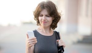 nő séta közben nézi a mobilját