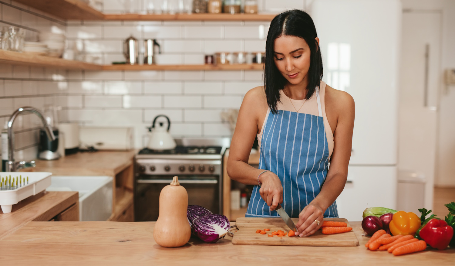fa vágódeszkén zöldséget aprít egy fiatal háziasszony