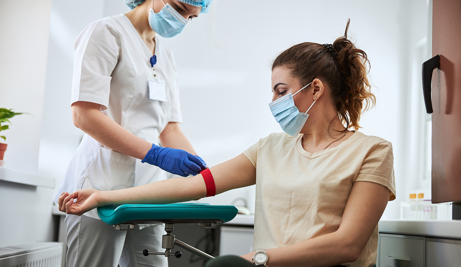 fiatal orvos érszorítót helyez egy női beteg karjára vénás vérvételhez