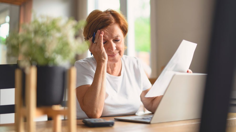 aggódó nyugdíjas hölgy a számlái fölött bosszankodik