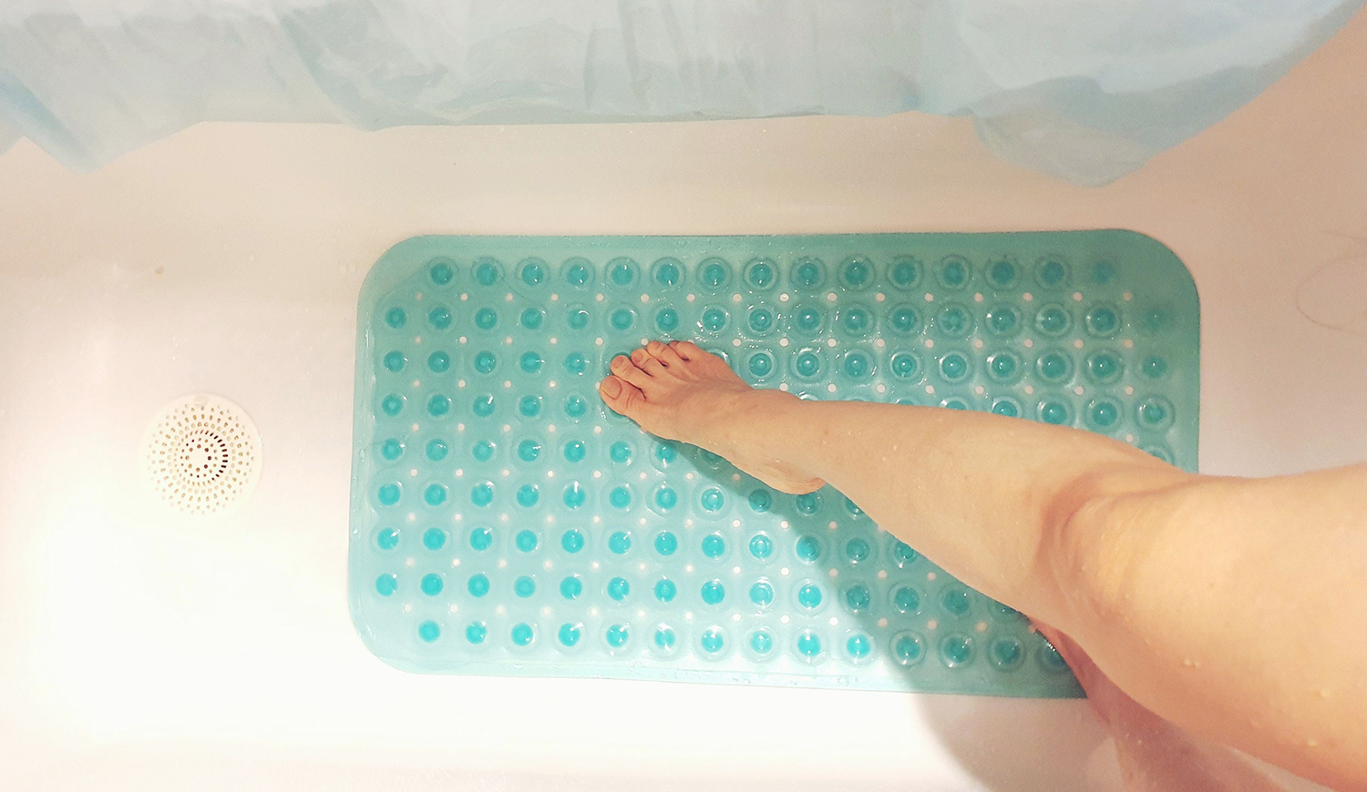 Nő a fürdőszobában csúszásgátló szőnyegbe lép a zuhanyzóban