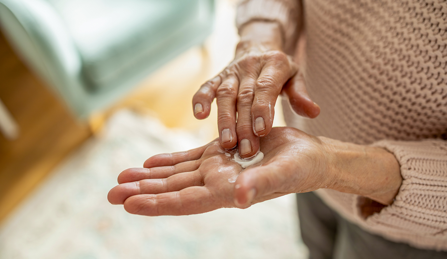 Idős nő kézkrémmel kenegeti a kezeit