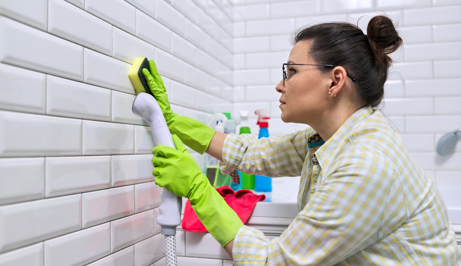 fürdőszobában csempét takarít egy nő