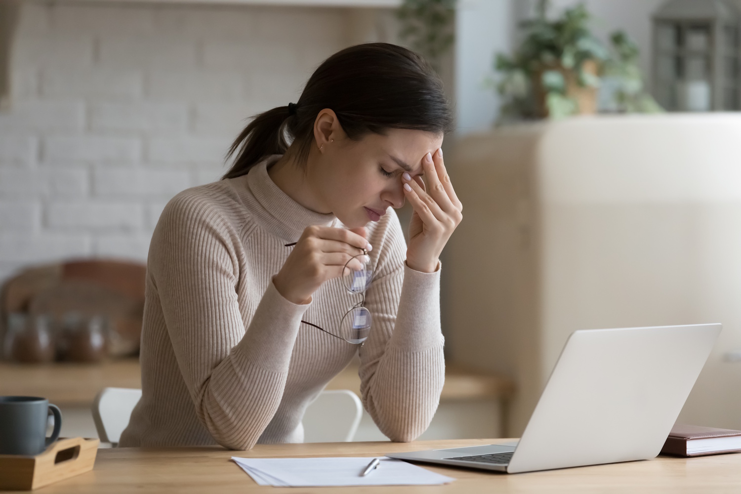 Egy lány fogja a fejét a laptopja előtt