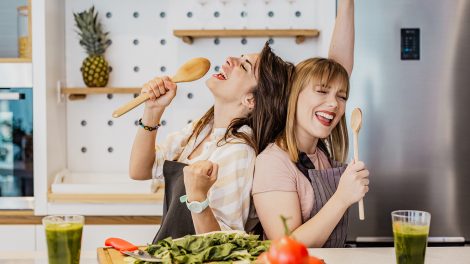 Két fiatal lány a konyhában fakanállal énekel