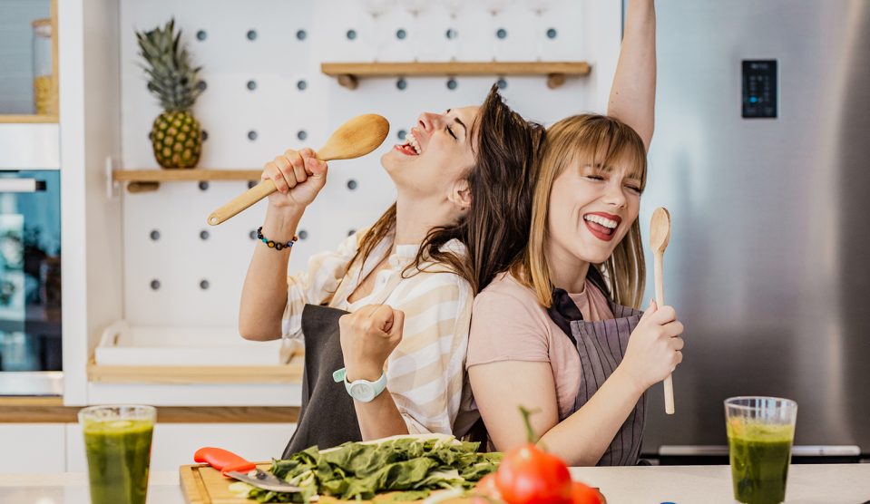 Két fiatal lány a konyhában fakanállal énekel