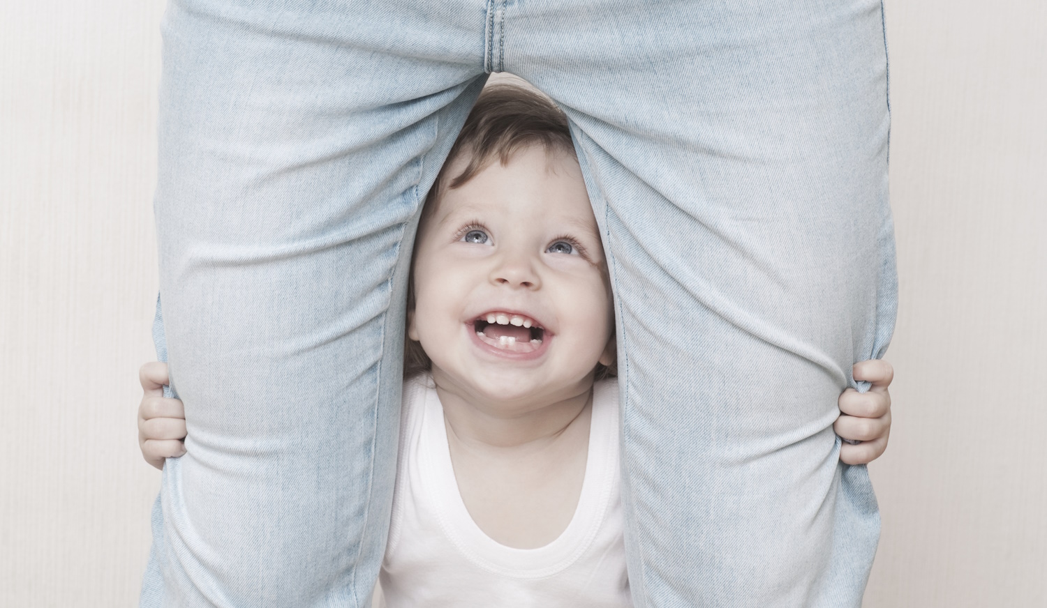 kacagó kisfiú áll az anyukája lába között