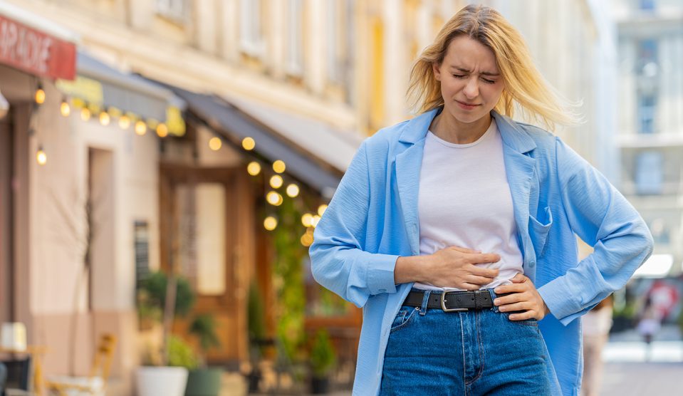 Nő fogja a gyomrát az utcán