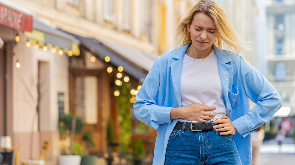 Nő fogja a gyomrát az utcán