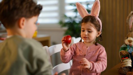 kislány a piros húsvéti tojását mutatja a bátyjának