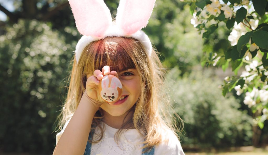 kislány húsvéti festett tojást tart a kezében nyuszifül van a fején