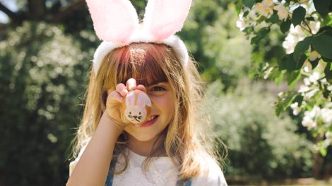 kislány húsvéti festett tojást tart a kezében nyuszifül van a fején
