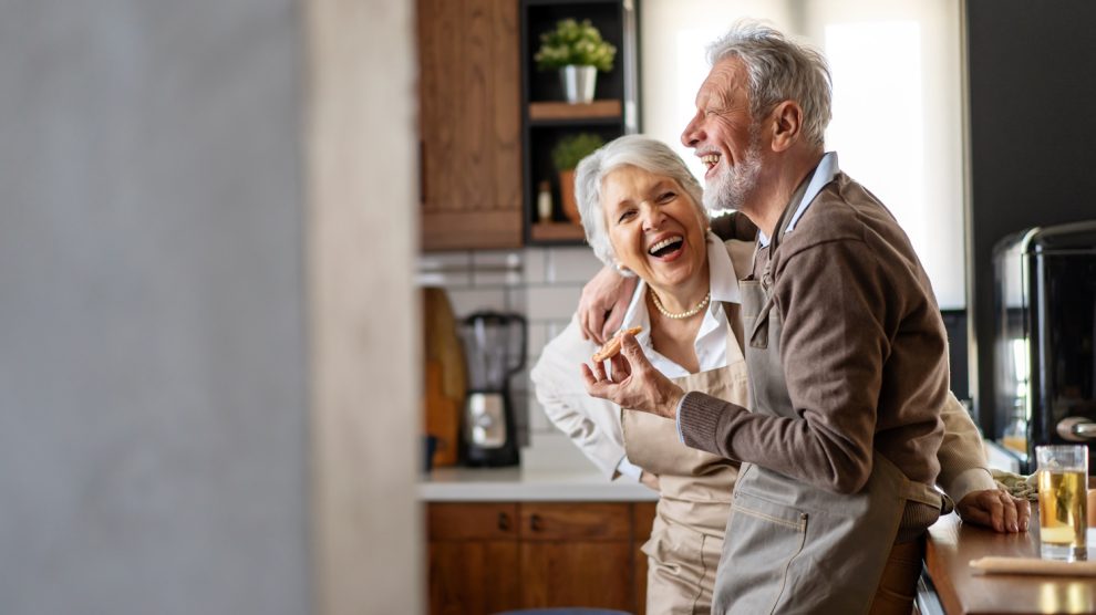 boldog idős pár mosolyog a konyháabn