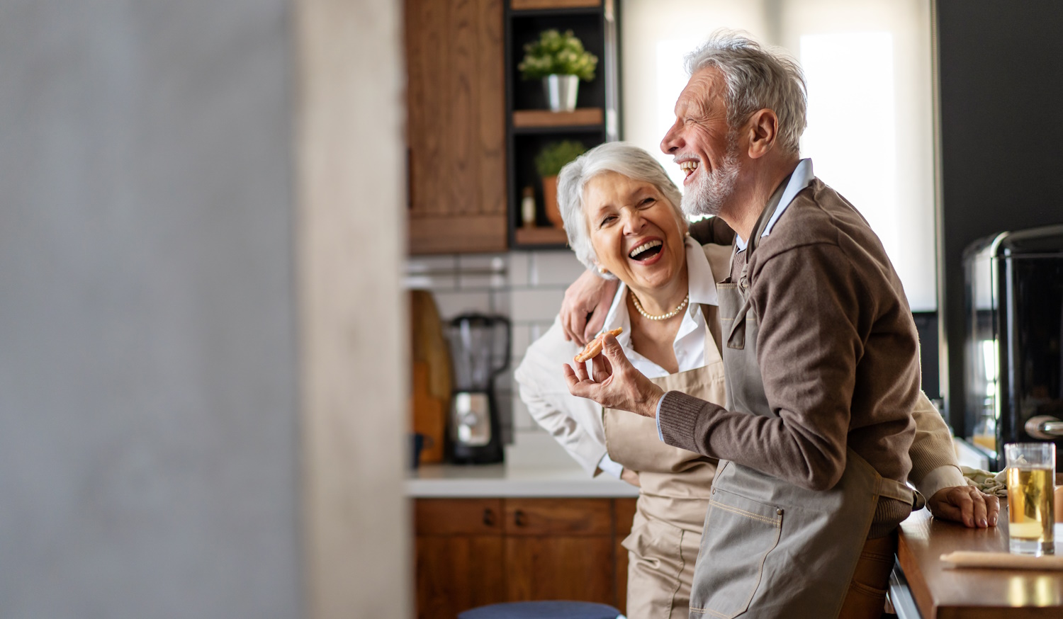 boldog idős pár mosolyog a konyháabn