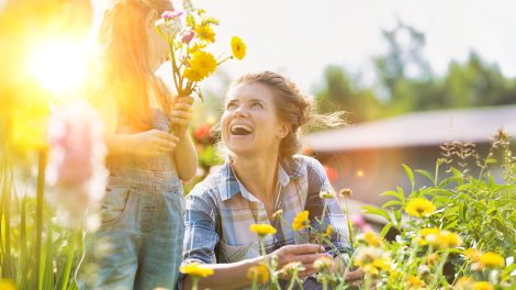 Anya és lánya szép színes virágokat szednek a kertben