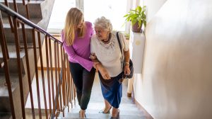 Fiatal nő segít egy idős nőnek a lépcsőn felmenni