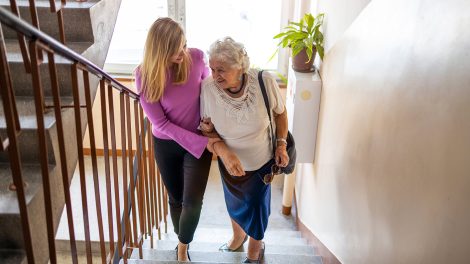 Fiatal nő segít egy idős nőnek a lépcsőn felmenni