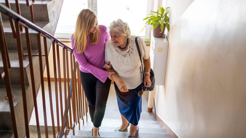 Fiatal nő segít egy idős nőnek a lépcsőn felmenni