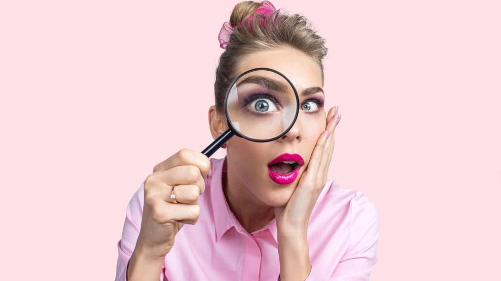 nő belenéz a nagyítóba