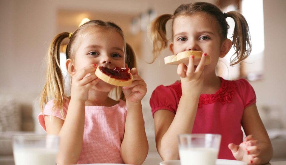 Két kislány lekváros kenyeret reggelizik